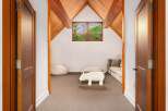 Step into this charming attic room, featuring a vaulted wooden ceiling and a cozy seating area perfect for relaxation.