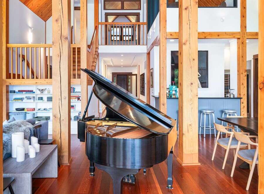 Experience luxury living in this grand home, featuring a stunning black grand piano as the centerpiece of a spacious, open-concept living area.