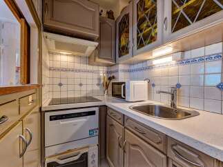 Discover this charming kitchen featuring a sleek induction stovetop and a modern dishwasher, perfect for effortless meal preparation.