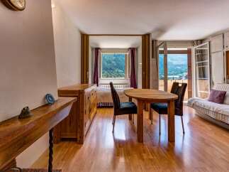 Experience breathtaking mountain views from this charming studio apartment, featuring a cozy dining area with a wooden table and chairs, perfect for intimate meals.