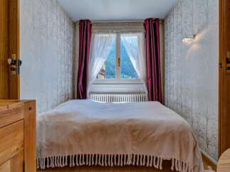 Experience cozy mountain living in this charming bedroom, featuring a comfortable bed draped with a soft, fringed throw.