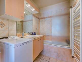 This bathroom features a convenient washing machine and a vanity with a sink and ample storage.