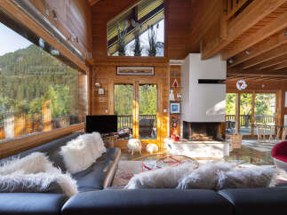 Experience breathtaking mountain views from this stunning log cabin living room, featuring a grand fireplace and expansive windows.