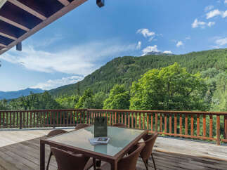 Enjoy breathtaking mountain views from this stunning property's expansive wooden deck, perfect for outdoor dining or relaxation.