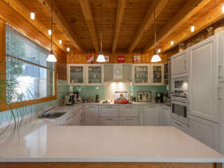 This charming kitchen boasts a rustic wooden ceiling with exposed beams and a track lighting system, creating a warm and inviting atmosphere.