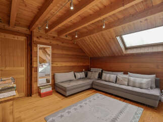 Experience rustic charm in this cozy wooden attic room, featuring a comfortable sectional sofa perfect for relaxation.