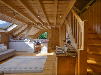 Discover this charming attic space, featuring a cozy living area with a comfortable sofa and a large rug, perfect for relaxation.