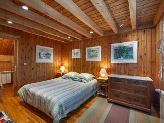 Experience cozy living in this charming wood-paneled bedroom, featuring a comfortable bed adorned with a colorful striped comforter.