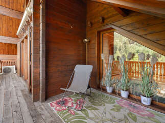 Enjoy the serene mountain views from this charming wooden balcony, perfect for relaxing with a cup of coffee.