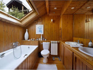 Experience rustic charm in this wood-paneled bathroom, featuring a deep soaking tub and a skylight offering natural light and treetop views.