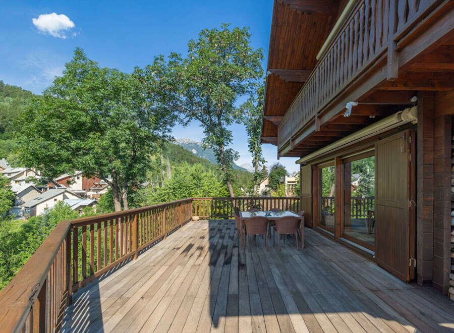 Experience breathtaking mountain views from this stunning wooden deck, perfect for outdoor dining and relaxation.