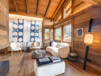 Experience luxurious alpine living in this stunning chalet, featuring a cozy living area with plush seating and a unique artistic mural.