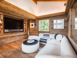 Experience rustic luxury in this stunning living room, featuring warm wood paneling throughout and a cozy sectional sofa.