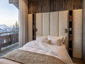 Experience ultimate luxury in this stunning mountain retreat bedroom, featuring a plush, upholstered headboard with integrated bookshelves and a cozy knit throw.