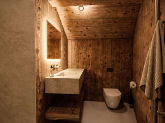 Experience rustic luxury in this charming bathroom, featuring warm wooden walls and a sleek, modern vanity with integrated lighting.