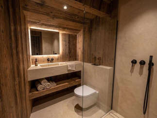 Experience rustic luxury in this modern bathroom featuring a floating concrete vanity with integrated sink and ample storage.