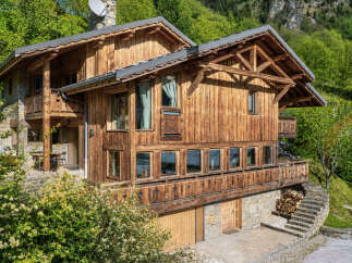 Experience the charm of this rustic wooden chalet nestled in a lush green mountain landscape.