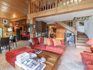 Experience rustic charm in this spacious living area featuring a grand wooden staircase and a cozy fireplace.