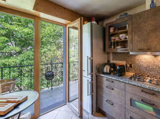 Enjoy the lush greenery from this charming kitchen, featuring a convenient balcony access through large glass doors.