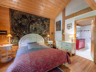 Experience rustic charm in this cozy bedroom featuring a large tapestry above the bed and warm wooden walls and ceiling.