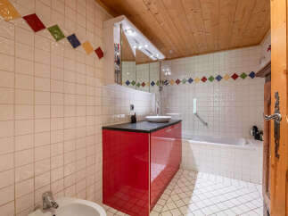 This charming bathroom features a vibrant red vanity with a sleek countertop and a modern vessel sink.