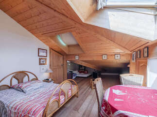 Experience rustic charm in this attic bedroom featuring a cozy bed with a striped comforter and a natural rattan headboard.