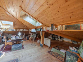 Discover this charming attic studio, bathed in natural light from skylights and featuring a warm, wood-paneled interior.