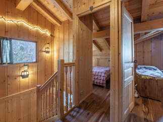 Experience rustic charm in this wooden chalet, featuring a cozy staircase with unique ski lift-inspired lighting and a warm, inviting ambiance.