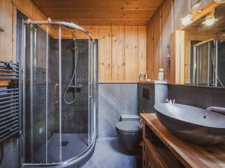 Experience rustic charm in this bathroom featuring a modern walk-in shower with dark tile and a sleek glass enclosure.