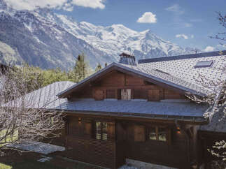 Experience the charm of this traditional wooden chalet nestled against a breathtaking mountain backdrop.