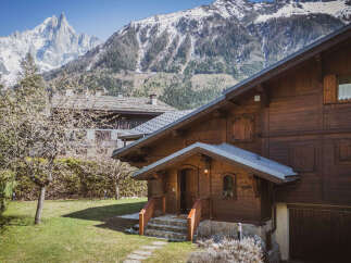 Experience the charm of this rustic wooden chalet nestled against a breathtaking mountain backdrop.
