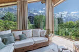Experience breathtaking mountain views from this cozy living room, featuring a comfortable white sectional sofa adorned with plush pillows.