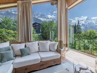 Experience breathtaking mountain views from this cozy living room, featuring a comfortable white sectional sofa adorned with plush pillows.