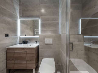 Experience modern luxury in this sleek bathroom featuring a floating vanity with ample storage and a large, illuminated mirror.