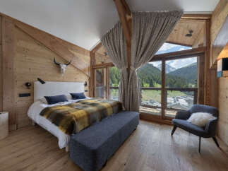Experience luxurious mountain living in this stunning bedroom featuring a cozy king-sized bed adorned with a warm, plaid throw.