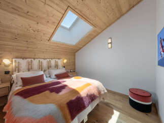 Experience cozy mountain living in this charming bedroom, featuring a sloped wooden ceiling with a skylight for natural light.