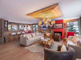 Experience luxurious mountain living in this stunning chalet-style living room, featuring a rustic wooden ceiling, a cozy fireplace, and a well-appointed bar area perfect for entertaining.