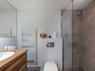 This modern bathroom features a sleek design with a floating vanity and a spacious glass-enclosed shower.
