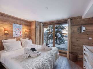 Experience cozy mountain living in this charming bedroom featuring rustic wood paneling and a plush white bed.