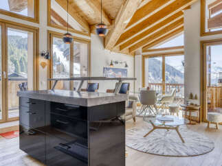 Experience luxury mountain living in this stunning chalet featuring a modern kitchen island with a sleek countertop and ample storage.