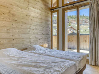 Experience cozy mountain living in this charming bedroom featuring two comfortable beds and a rustic wooden wall.