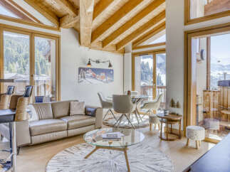 Experience luxurious mountain living in this stunning chalet featuring a spacious open-plan living area with a comfortable leather sofa and a modern glass dining set.