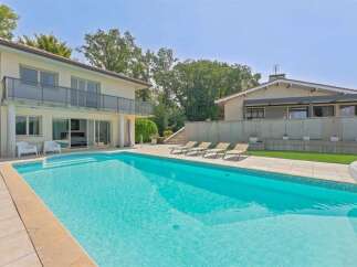Experience luxury outdoor living with this stunning property featuring a sparkling swimming pool and ample lounge chairs for relaxation.