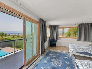 Experience breathtaking lake and mountain views from this stunning bedroom, featuring a private balcony with a refreshing pool.