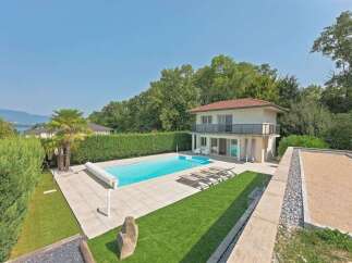 Experience luxurious outdoor living with this stunning property featuring a sparkling swimming pool and ample lounge chairs perfect for sunbathing.