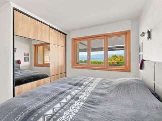 Experience serene living in this beautifully appointed bedroom, featuring a spacious bed with a patterned duvet and a large wardrobe with mirrored doors.