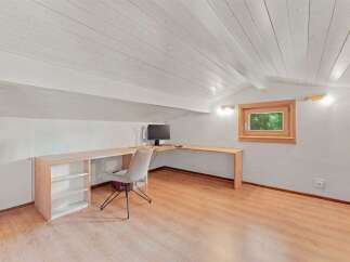 Discover this charming attic workspace, featuring a spacious L-shaped wooden desk perfect for productivity.