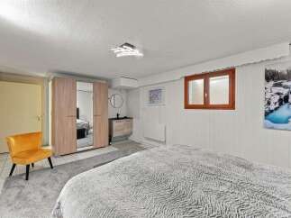 Discover this charming bedroom featuring a plush grey rug and a vibrant orange accent chair, perfect for relaxation.