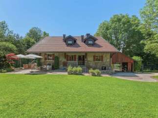 Charming country house with a spacious green lawn and mature trees, perfect for outdoor living.