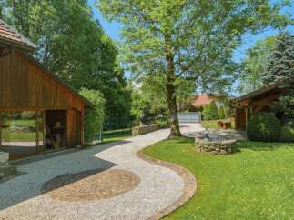 Discover this charming property featuring a rustic wooden garage with ample space and a picturesque gravel driveway leading to a well-maintained lawn.